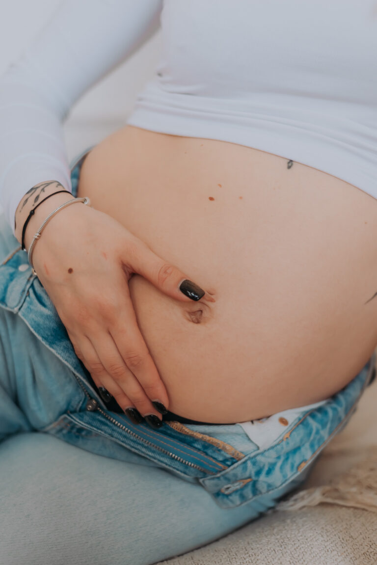 Detail těhotenského bříška s rukou nastávající maminky