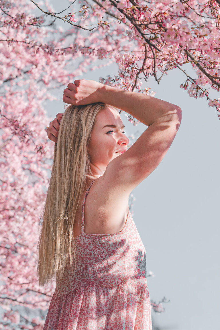 Žena v růžových šatech pod rozkvetlou sakurou – portrétní fotografie