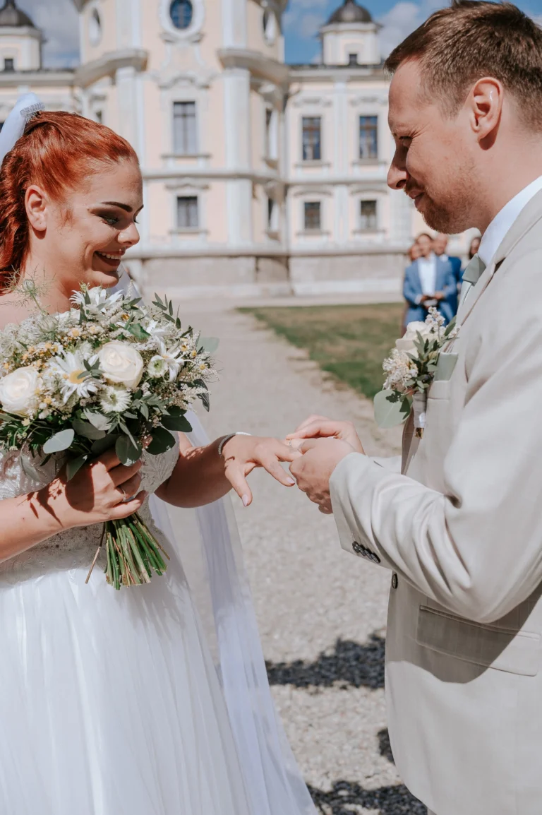 Detail výměny snubních prstenů během svatebního obřadu.